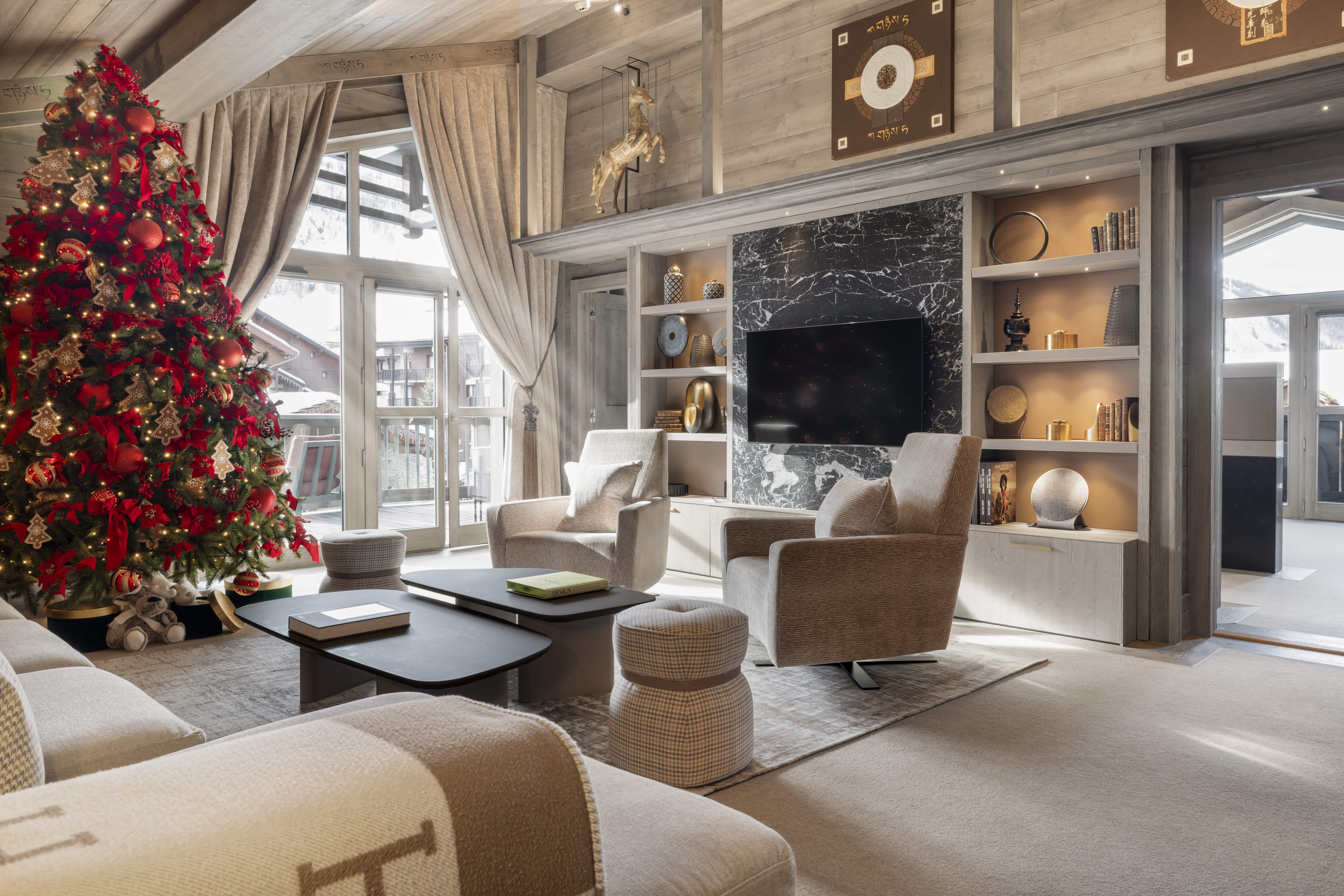 Salon élégant du K2 Chogori Val d’Isère avec cheminée décorative et sapin de Noël