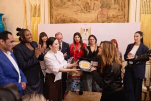 Groupe de personnes dans une piece luxueuse. Au centre une personne recoit un prix. Forum Listen to Her Parole 2026