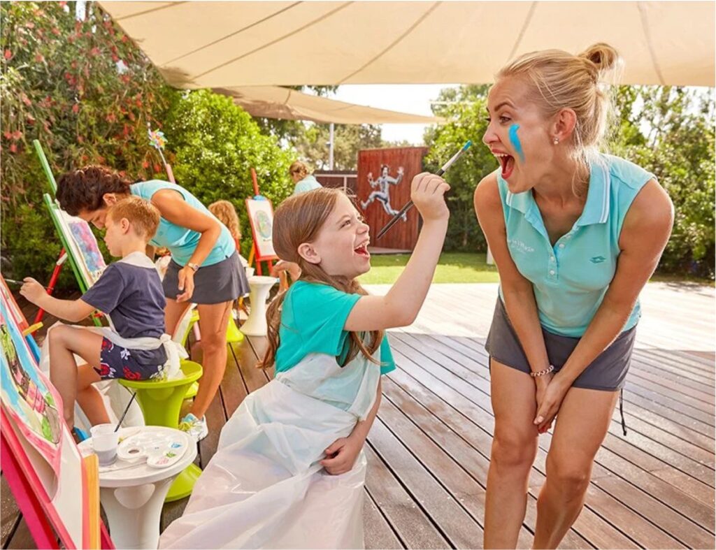 Enfant qui peint le visage d'une femme avec de la peinture bleue au Forte Resort