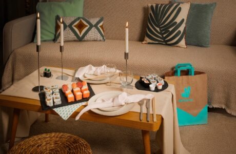 intérieur sobre, table garni de sushi evec deux bougies, à côté un sac de livraison de Deliveroo, une sorte de Date Night