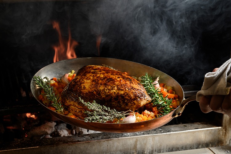 viande sauté à la poêle accompagné de feuilles de thym, cuisiné au feu de bois